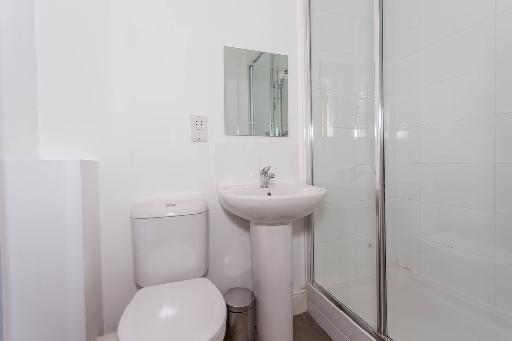 En-suite bathroom with shower, wall mounted mirror above sink