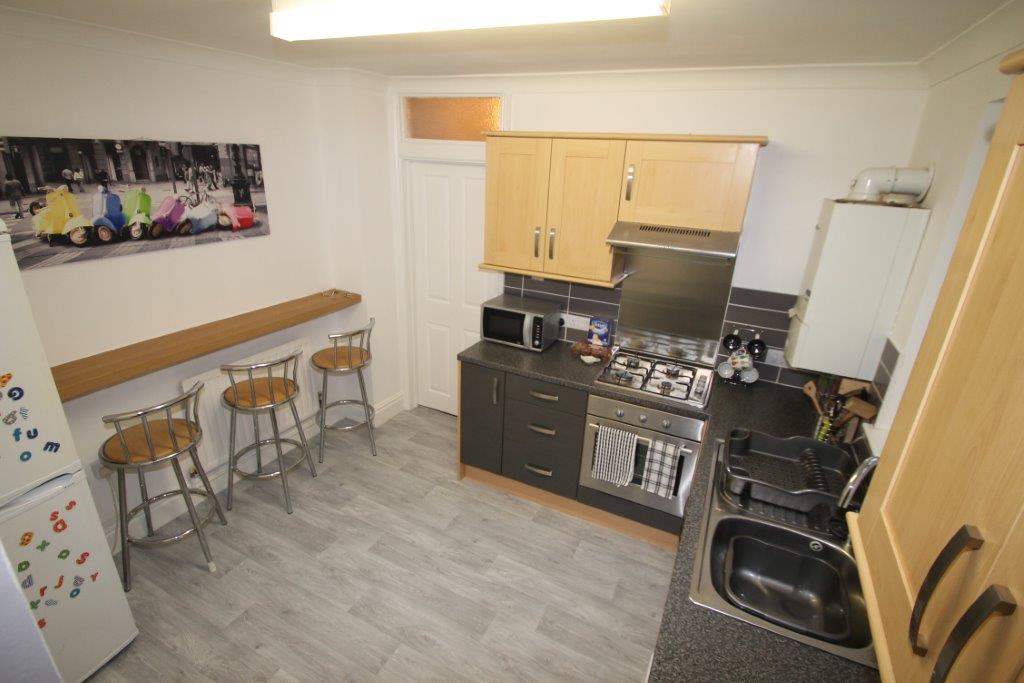 kitchen with gas hobs and cooker, fridge freezer, washing machine and breakfast bar with three bar stools