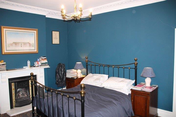 Student bedroom blue walled with double bed, two bedside tables