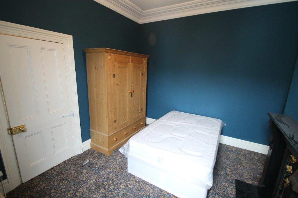 Blue walled student bedroom with double bed, two large two door wardrobes, one with drawers
