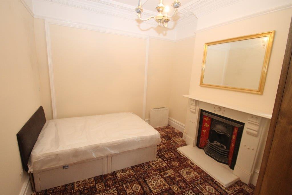 Student bedroom with double bed, two door wardrobe, white feature fireplace with large window