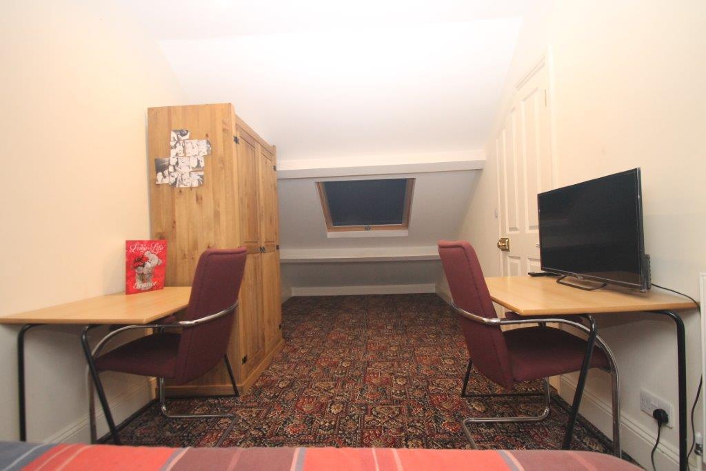 Sixth student bedroom with double bed, two door wardrobe, two desks and large skylight window