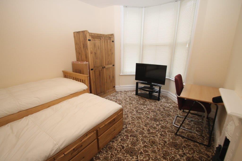 Fourth student room with single bed turn into two, two door wardrobe, desk, tv and tall bay windows