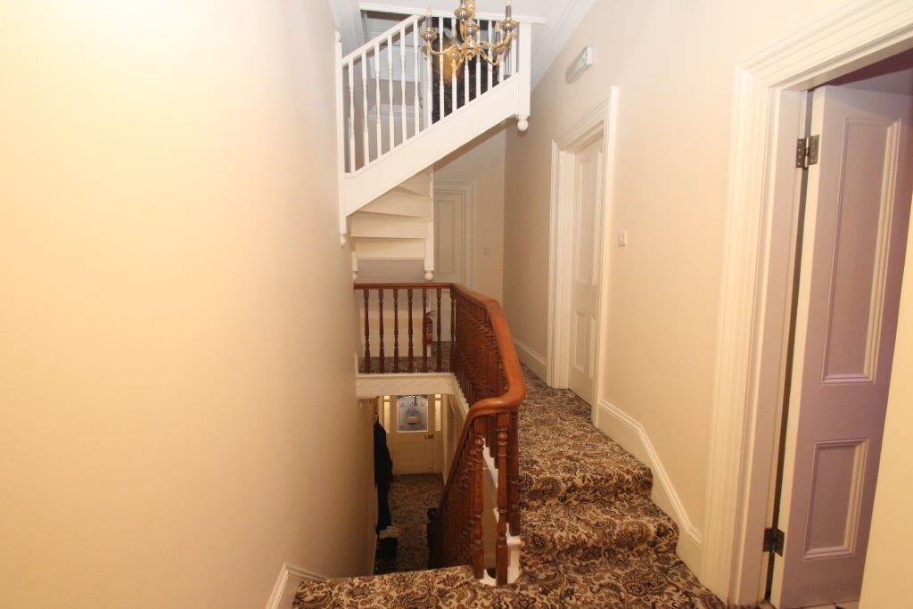 First floor hallway showing entrance student bedrooms and stairs heading to student room