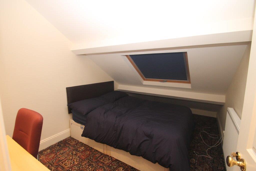 Fifth student bedroom with double bed, desk and large skylight window