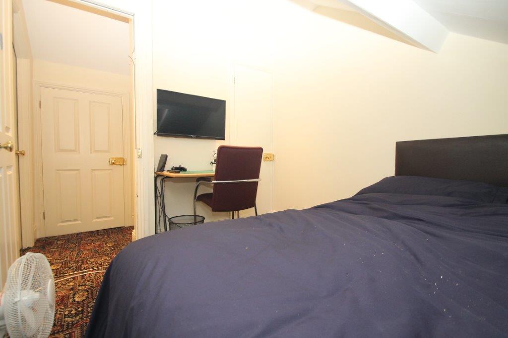 Student bedroom with double bed, desk and wall mounted tv