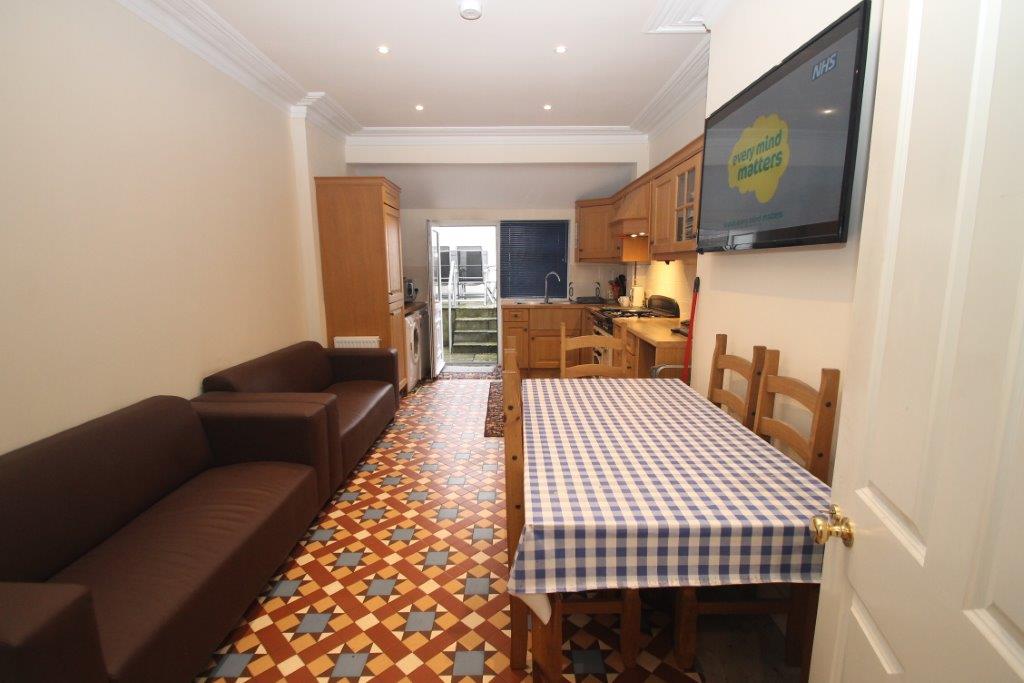 Shared living area with two double sofas, six seater dining table leading to shared kitchen