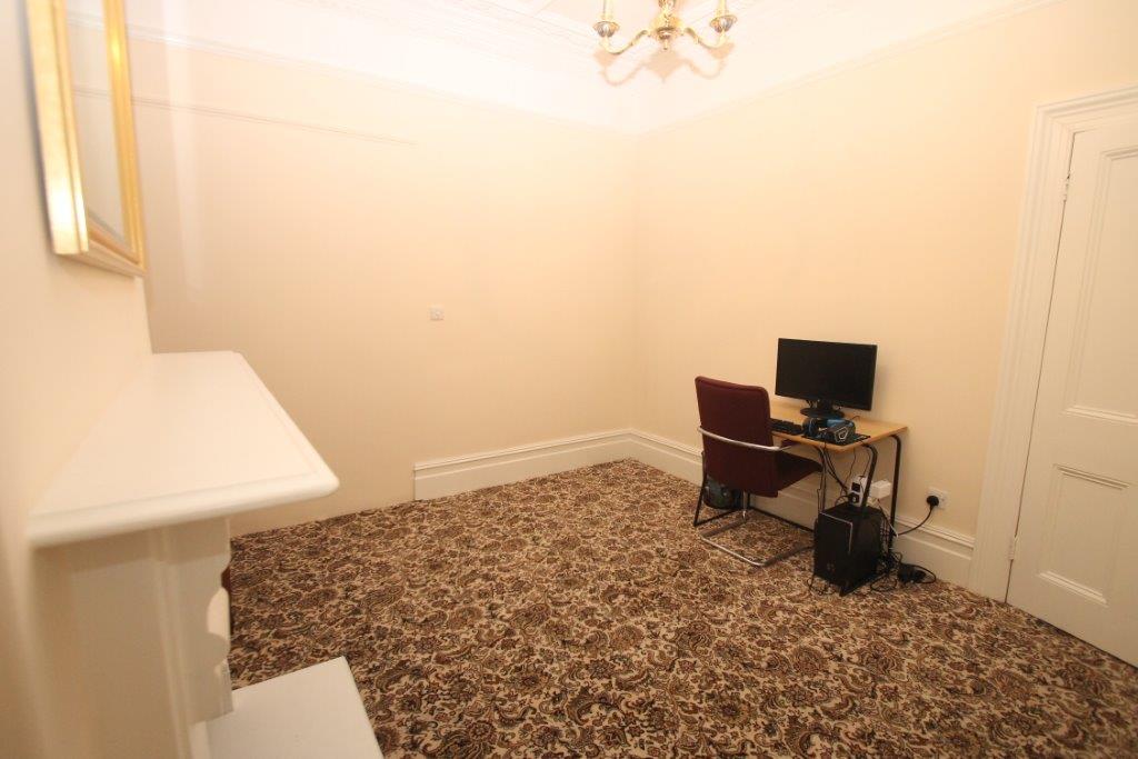 Room with white feature fire place, mirror on wall and desk