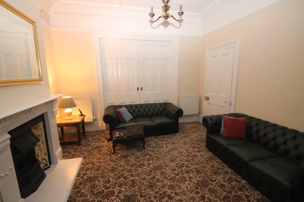 Shared living room with two seater sofa, three seater sofa and large mirror on wall