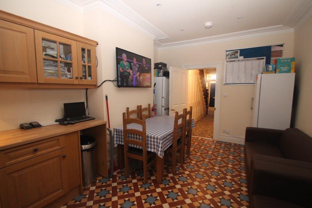 Living area with five seater dining table, two fridge freezers and hallway leading to the front of the property