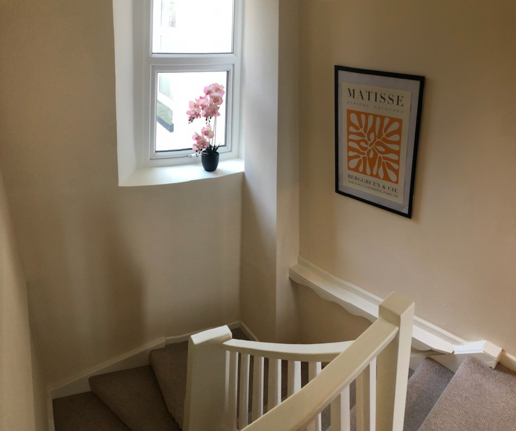 Staircase from top landing with orchid in window