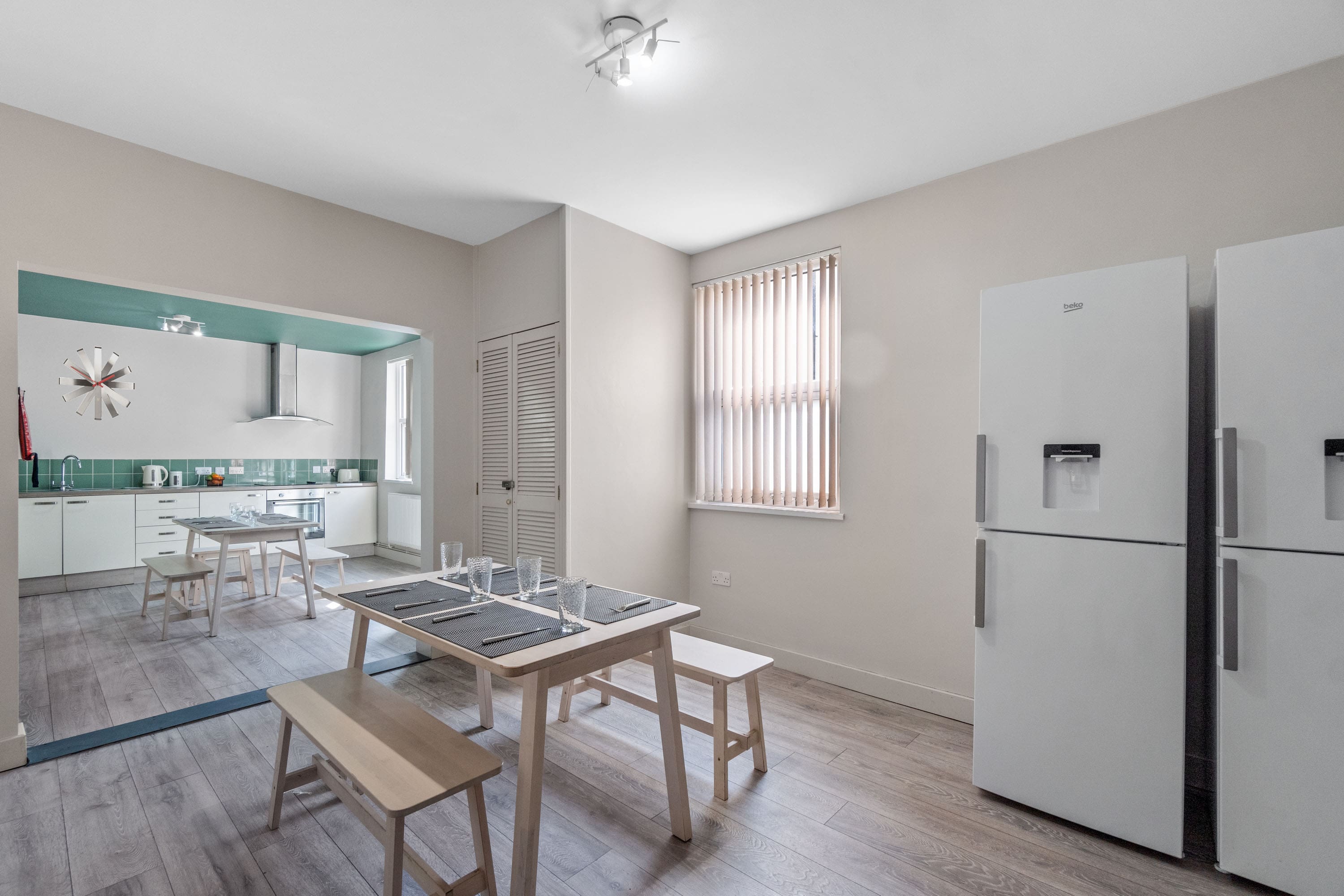 Spacious dining and kitchen area with two fridge freezers, two dining tables with bench seating and built-in cupboard space