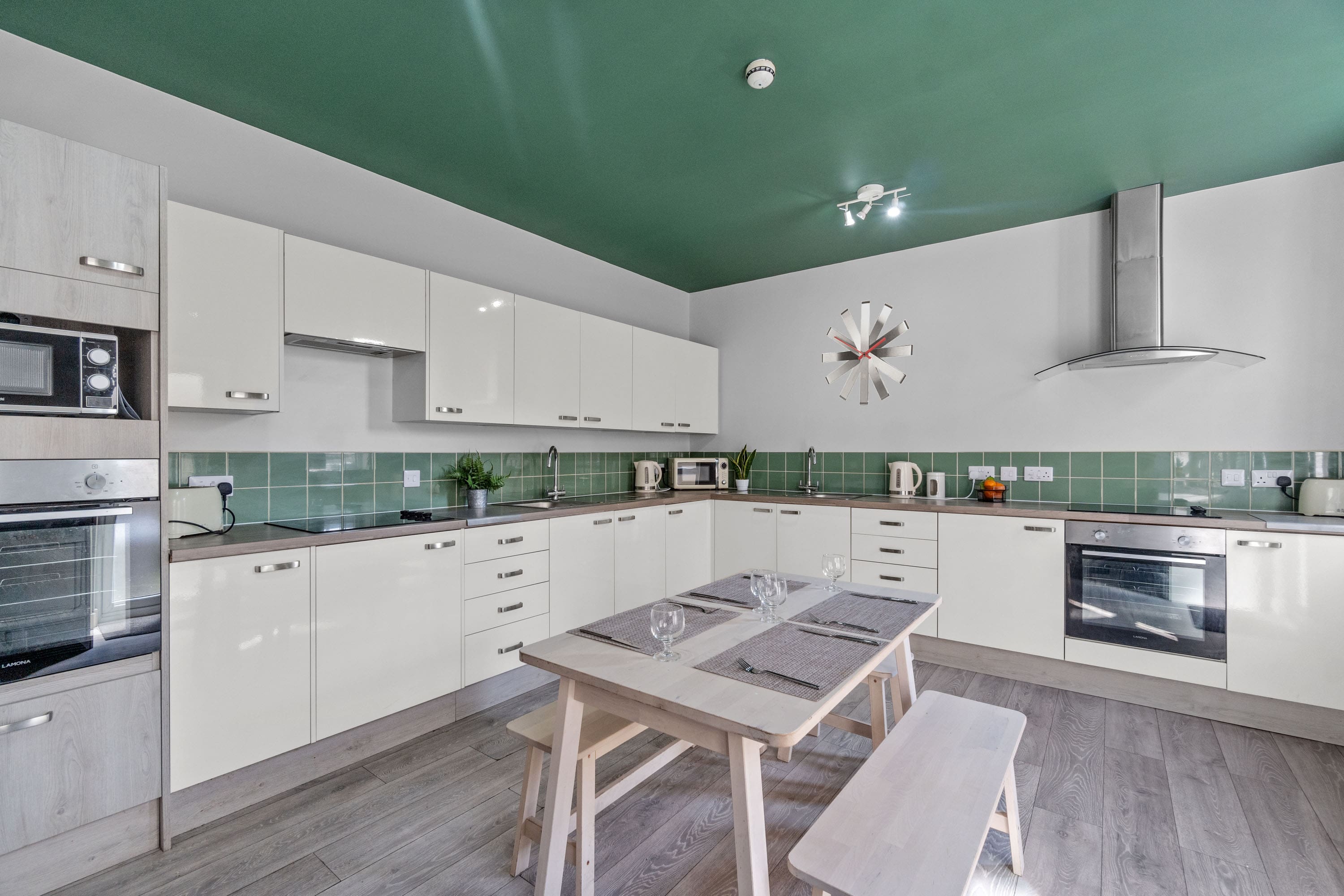 modern kitchen with two cookers with induction hobs, dining table in the middle with bench seating 