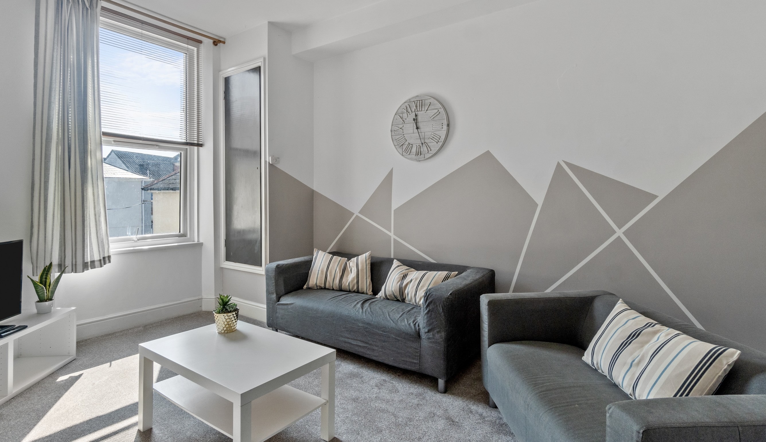 Living area with two grey sofas, white coffee table, tv on white tv stand