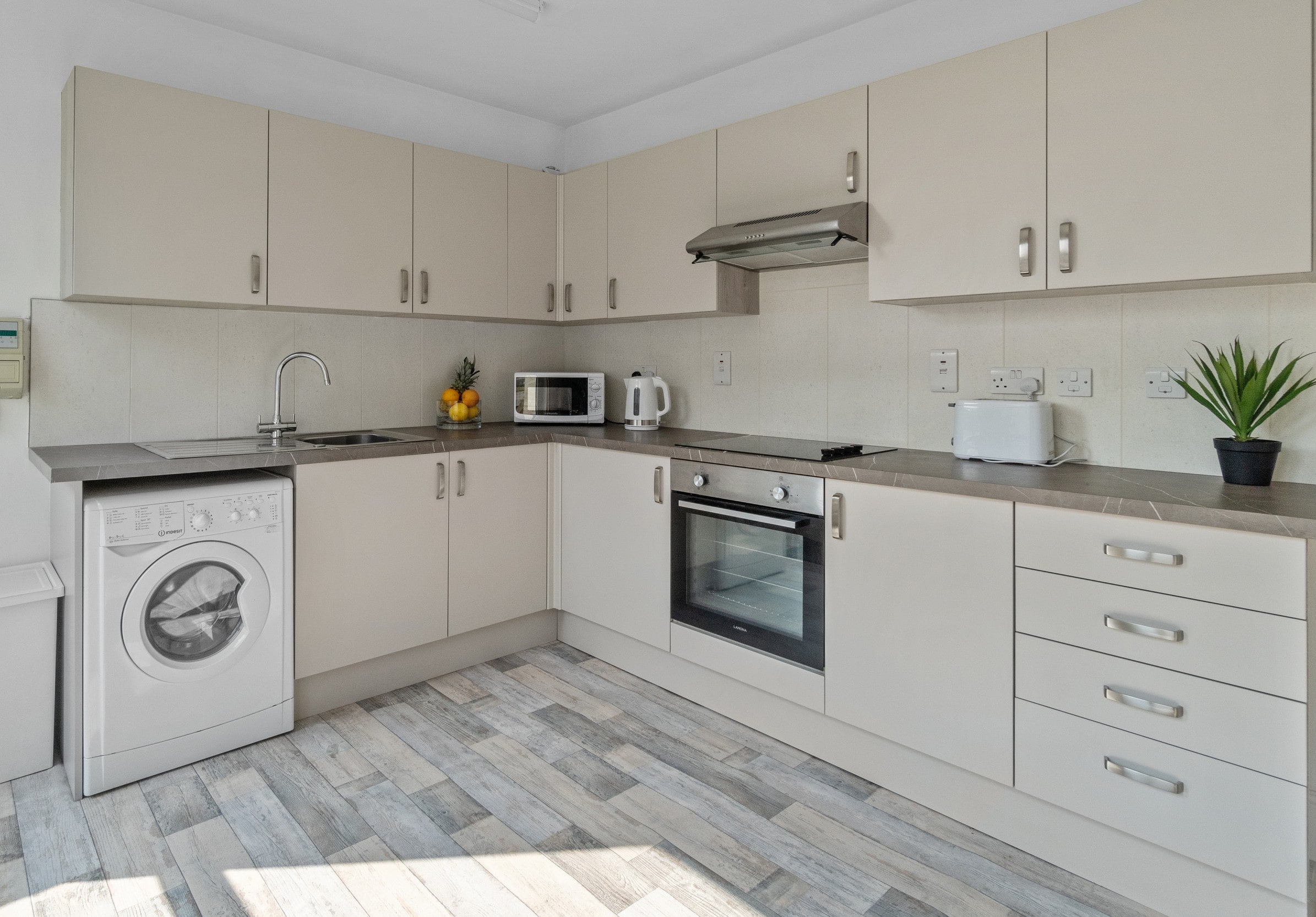 Another corner of kitchen area with induction hobs and cooker with washerdryer and sink