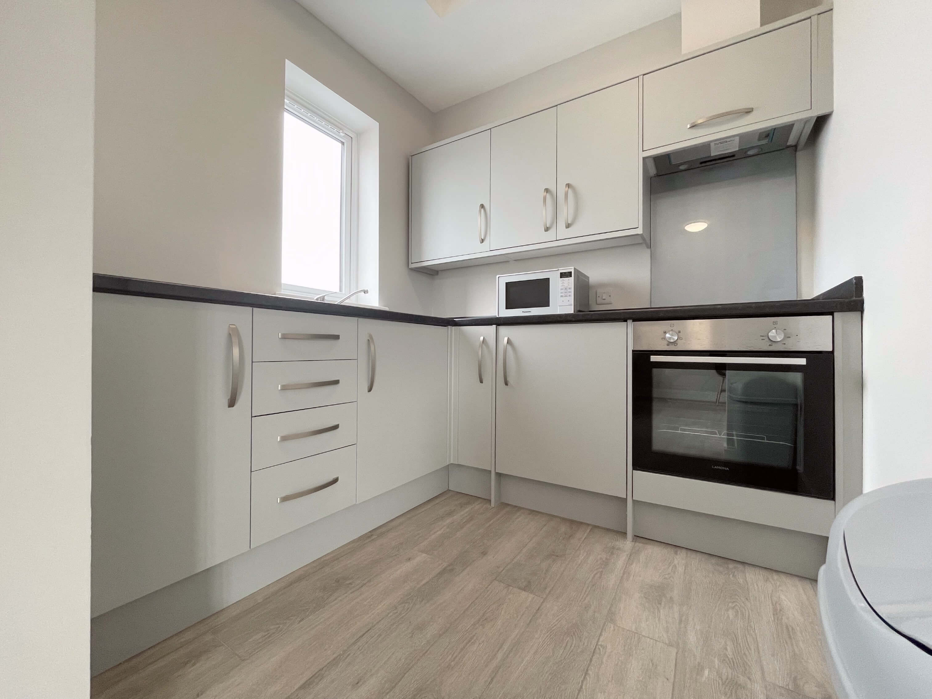 Kitchen area with small fridge freezer, cooker, hobs and microwave