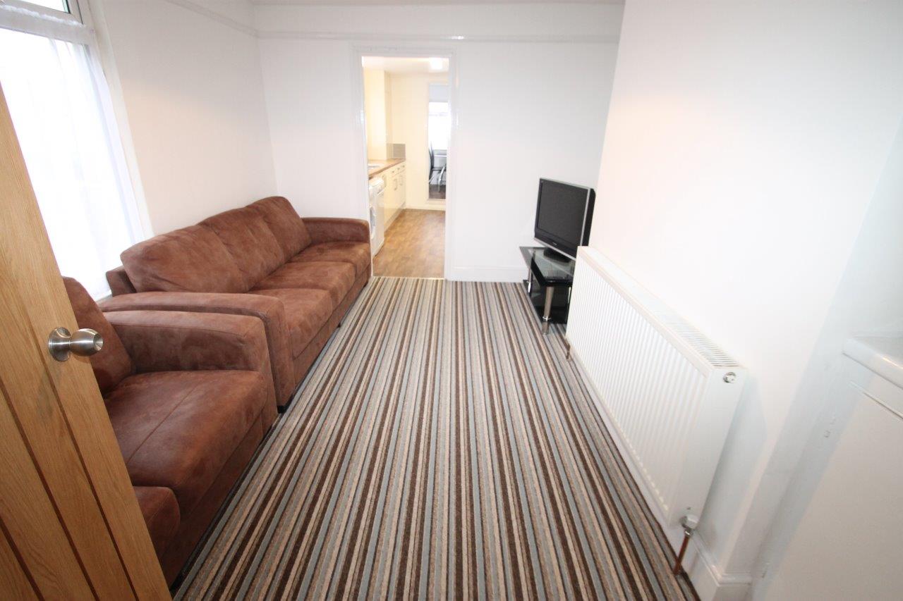 Shared living room with three and two seat sofa leading into shared kitchen