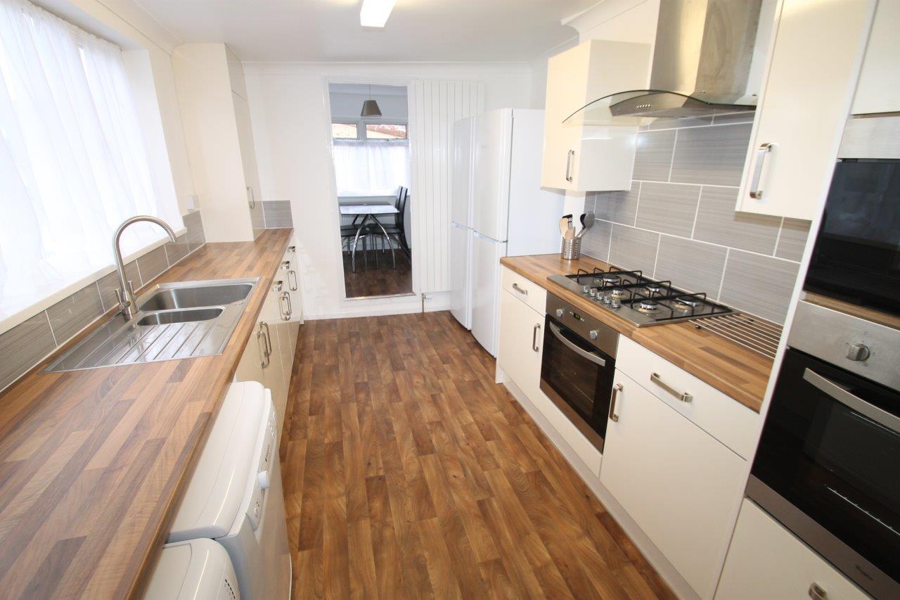 shared kitchen with gas cooker, two ovens, fridge freezers leading into dining area