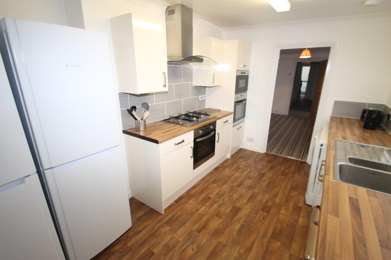 shared kitchen with gas cooker, two ovens, fridge freezers leading into living room