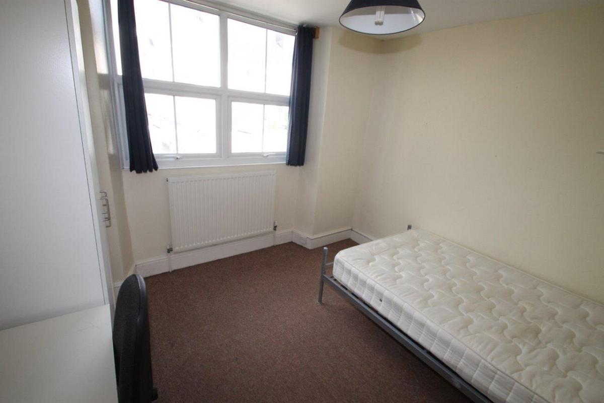 student bedroom with double bed, two door white wardrobe and desk with black office chair