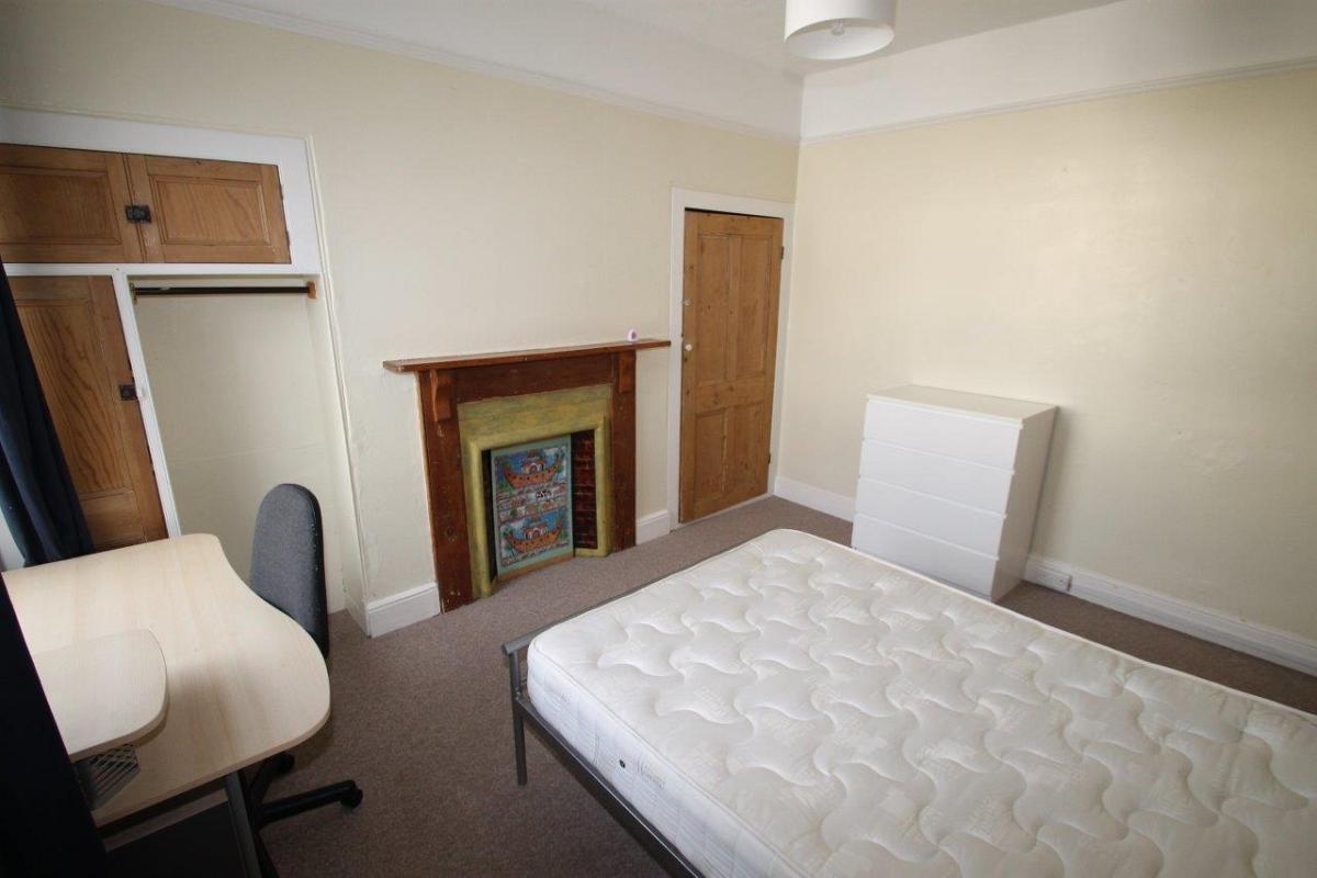 student bedroom with double bed, chest of drawers, white chest of drawers, clothing rail and storage cupboards