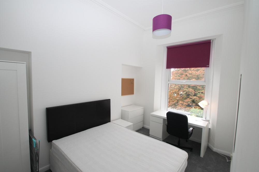 student bedroom with double bed, bedside table, chest of drawers, two door wardrobe and pinboard on wall