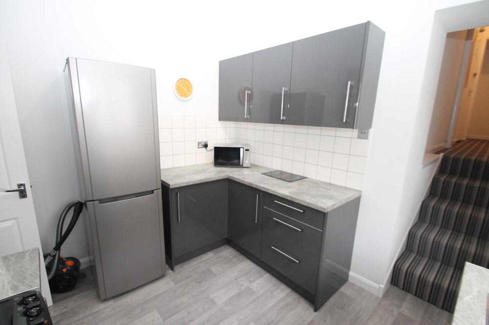 grey kitchen with fridge freezer, induction hobs and cooker and microwave