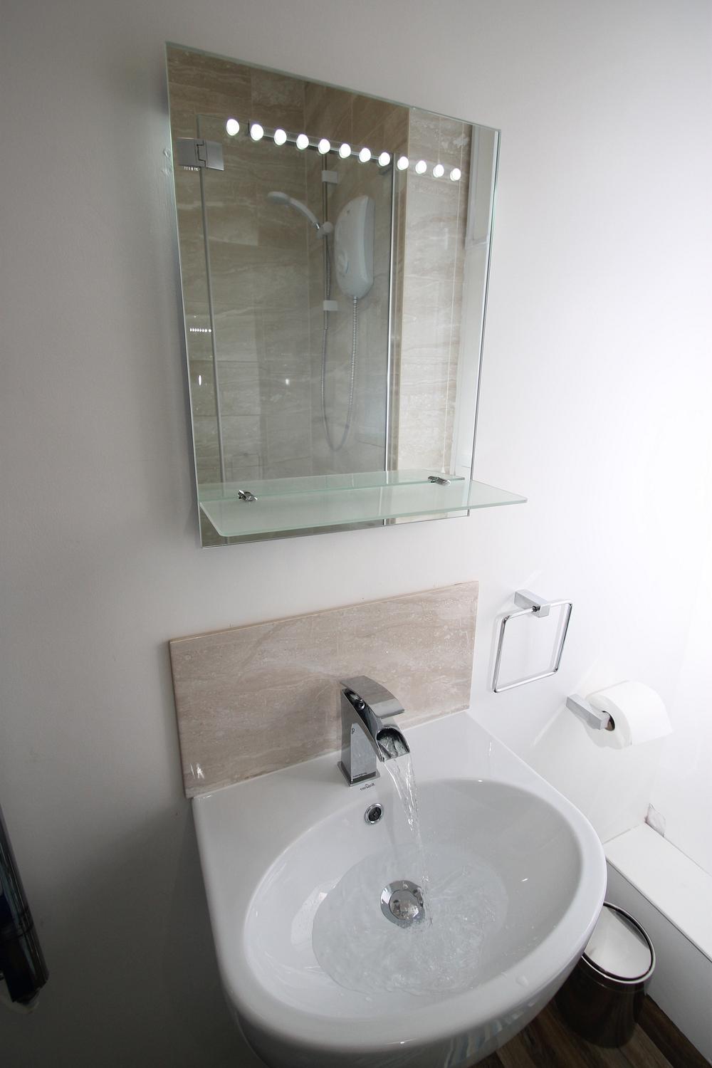 mirror with lights and shelves above sink