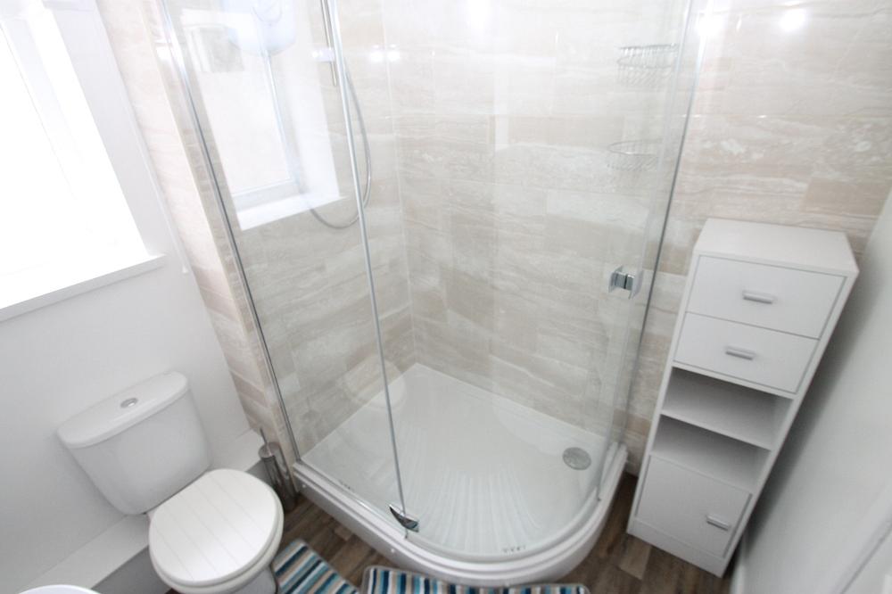 bathroom with corner shower, white tall chest of drawers and sink