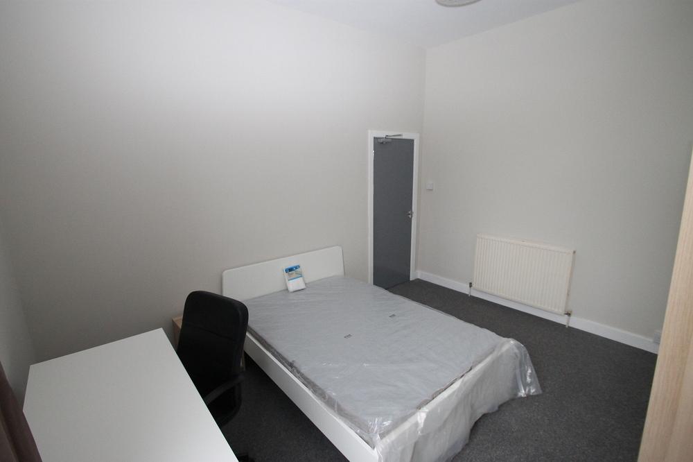 student bedroom with double bed, desk with black office chair and two door wardrobe
