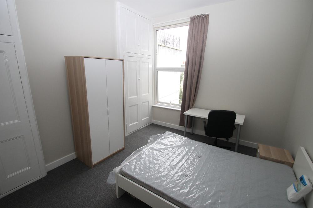 student bedroom with double bed, two door wardrobe, white desk with black office chair