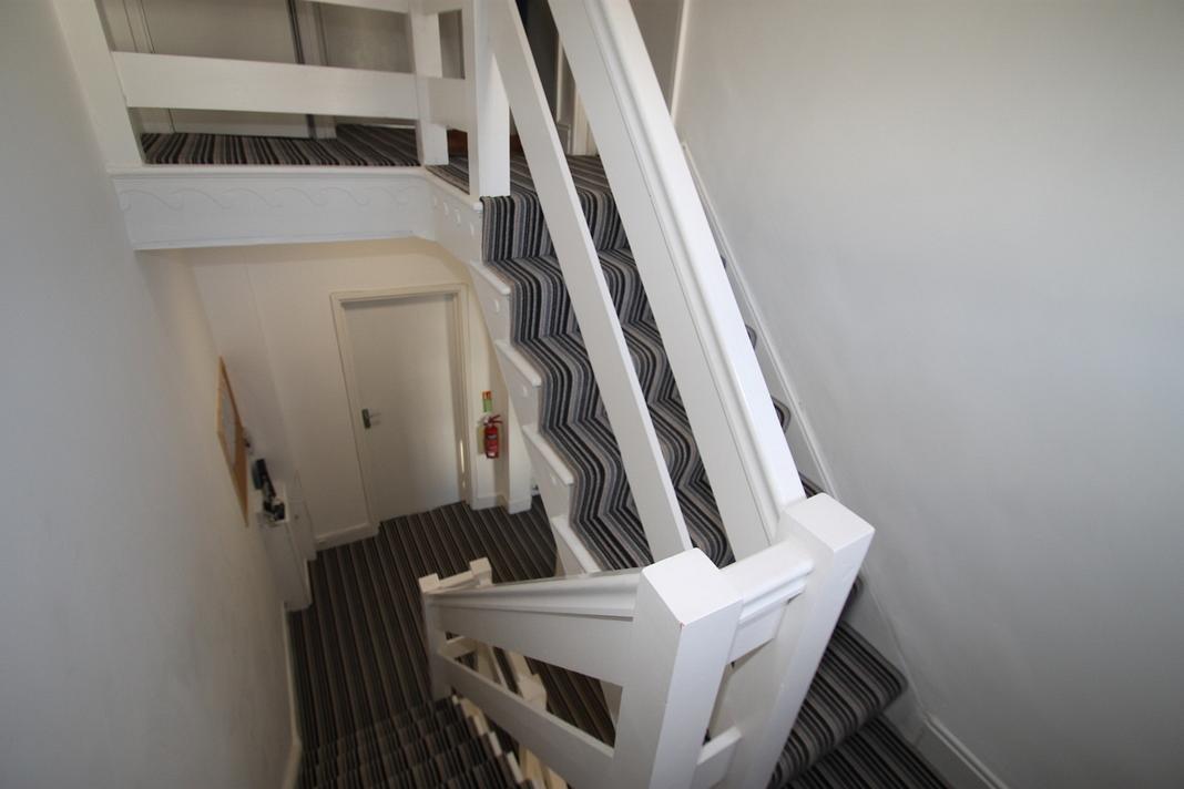 stairway of property leading down the communal areas and upstairs to bedrooms