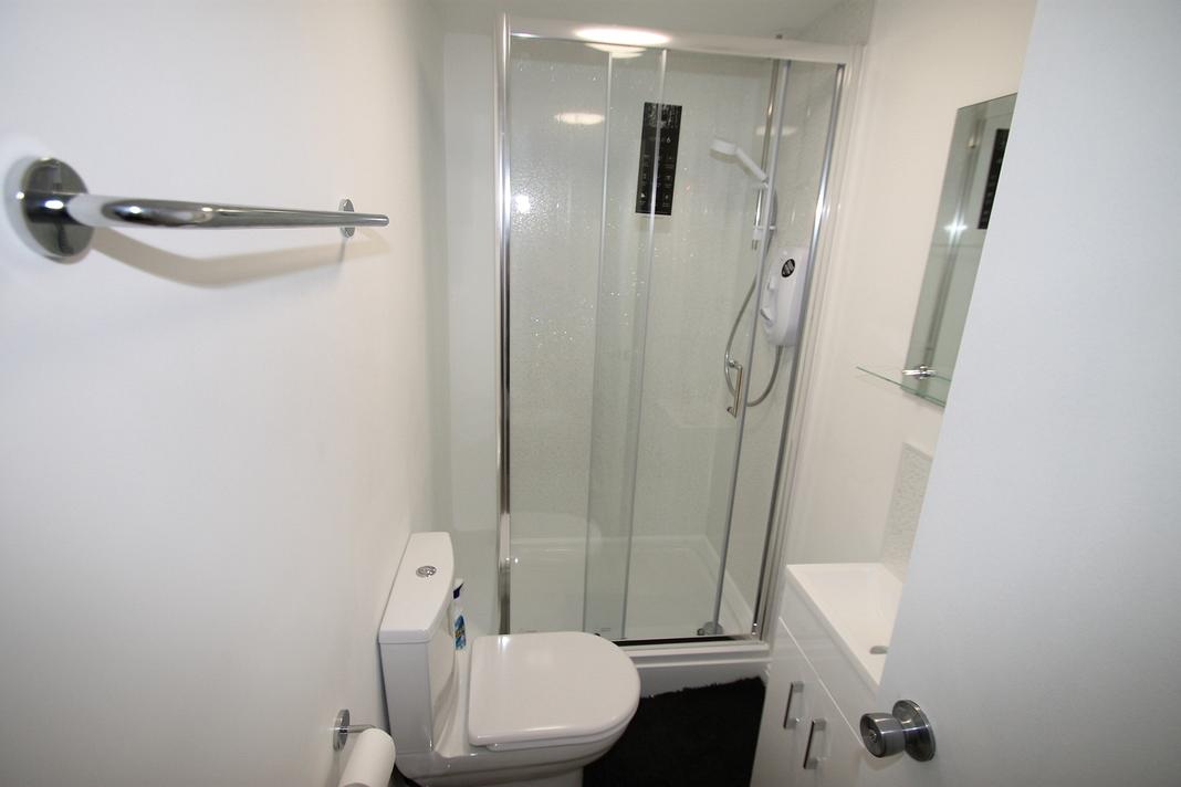shared bathroom with shower and mirror mounted above sink