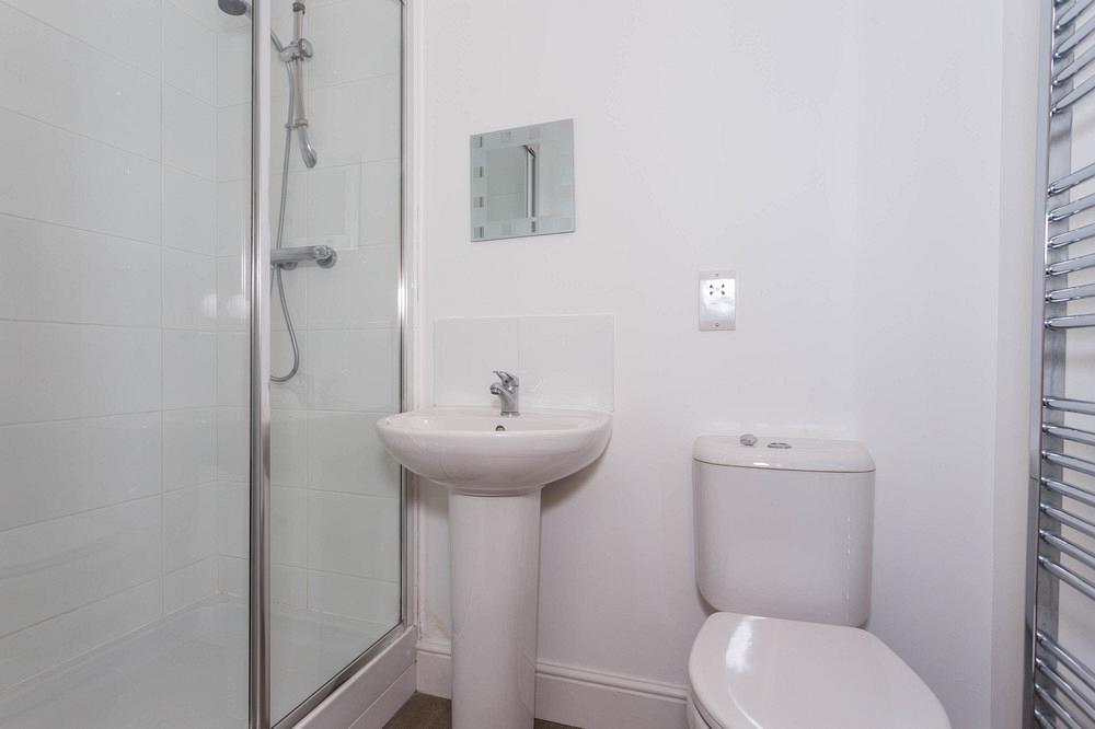 En-suite bathroom with shower and small mirror above sink