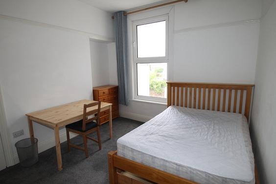 student bedroom with double bed, desk with chair and just of drawers