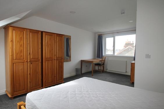 large student bedroom with double bed, desk with chair, chest of drawers, x2 two door wardrobes and full length mirror