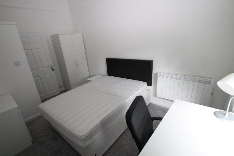 student bedroom with double bed, two door wardrobe, bedside table, desk with black office chair