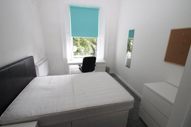 student bedroom with double bed, chest of drawers, desk with office chair, full length mirror and pinboard