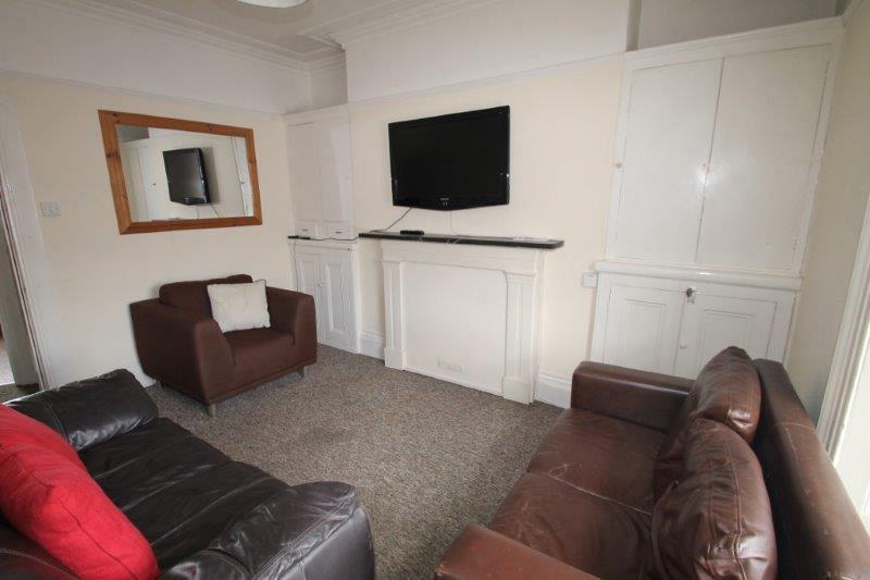 living room with two leather two-seater sofas, brown armchair, tv mounted on wall and large mirror
