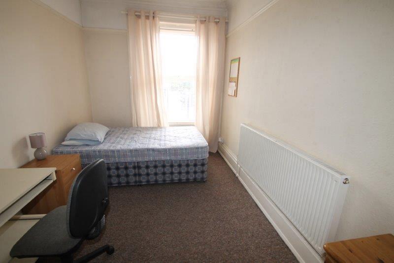 student bedroom with double bed, chest of drawers, bedside table and desk with grey office chair