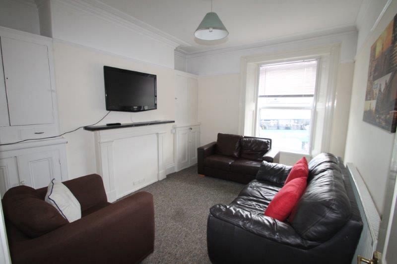 living room with two leather two-seater sofas, brown armchair and wall mounted tv
