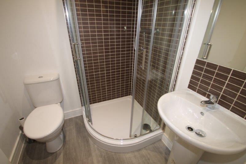 En suite with brown tiling, corner shower and mirror above sink]