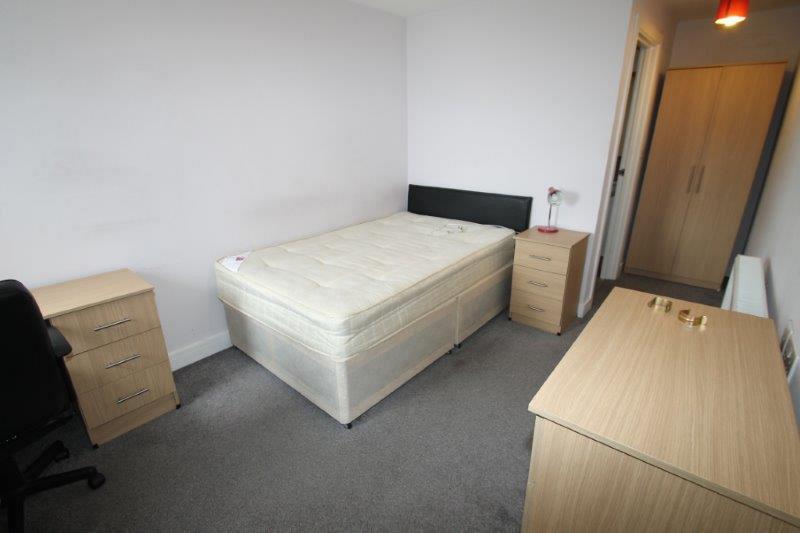 Student bedroom with bedside table, chest of drawers, two door wardrobe and desk with black office chair