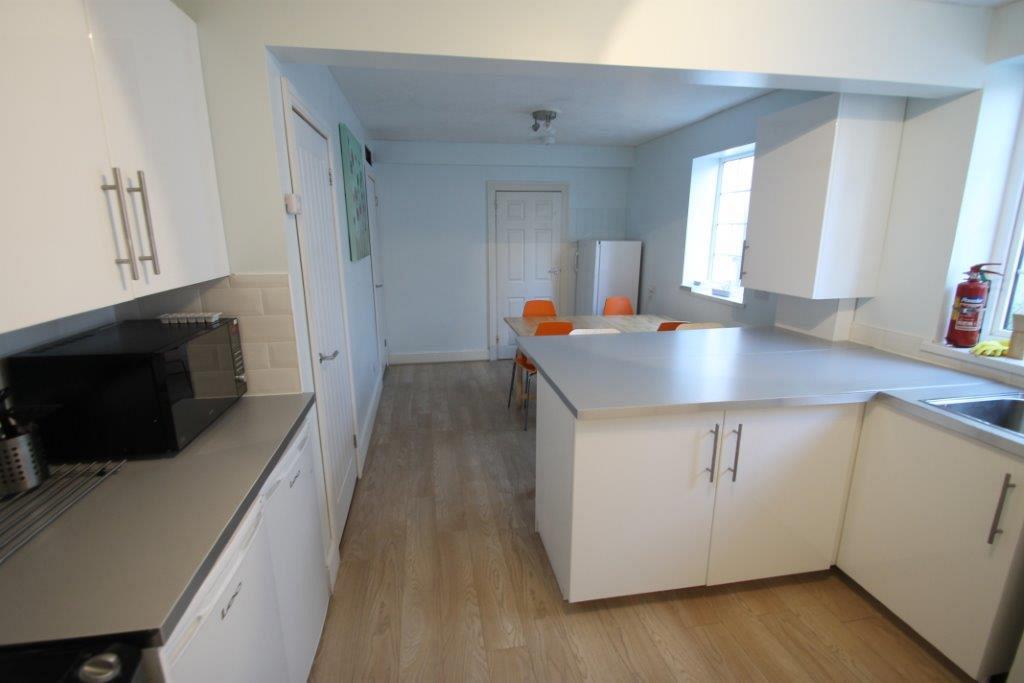 kitchen with fridge freezer, two small fridges, gas hob and cooker with sink