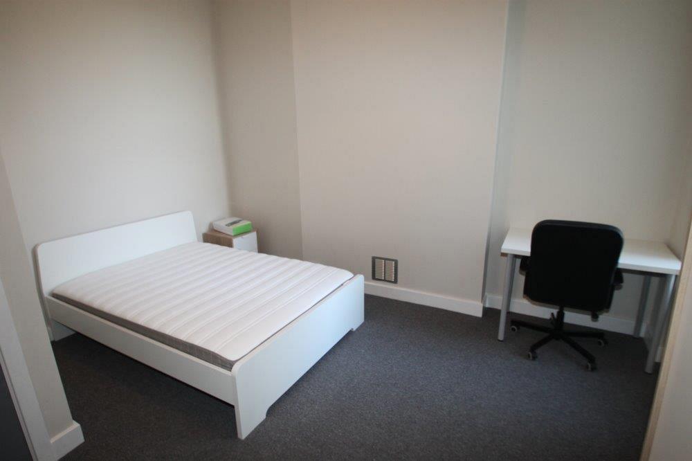 first student bedroom with double bed, bedside table, white desk with black office chair