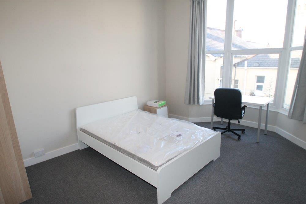 second student bedroom with double bed, desk with black office chiair and two door wardrobe