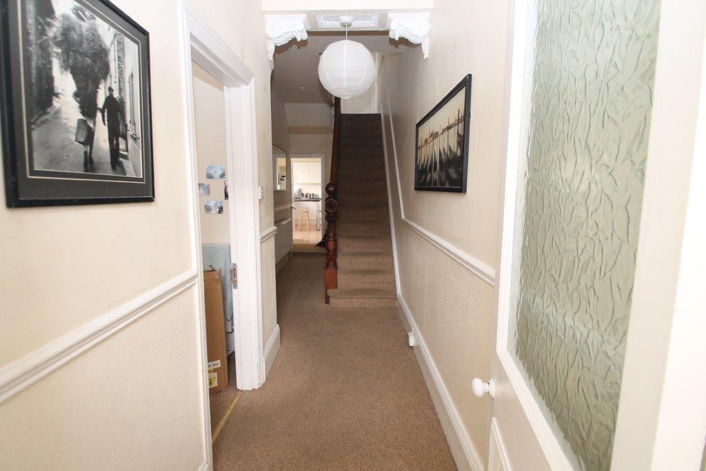 Hallway from the front door, showing entrance to first student bedroom, hallway leading to kitchen and stairs towards second floor