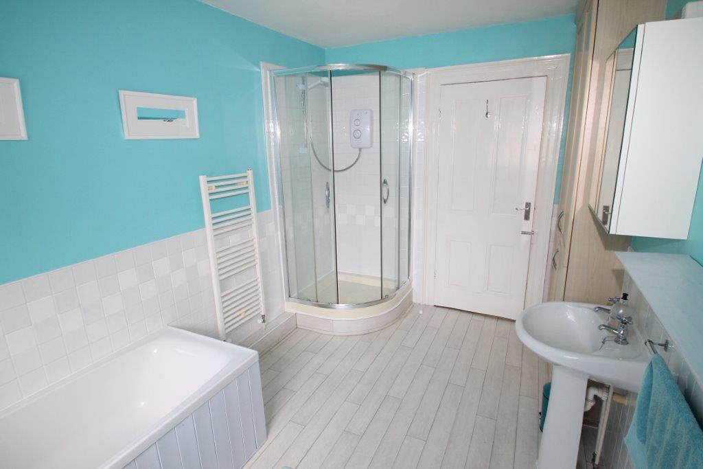 shared bathroom with blue tiles with corner shower, bath and cupboard storage space