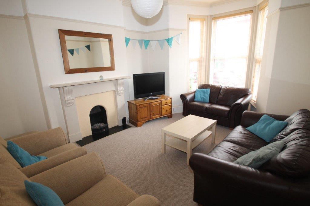 shared living room with two leather two-seater sofas, two armchairs, coffee table and television on tv stand