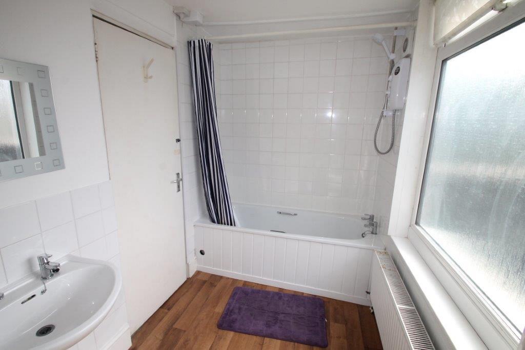 Shared bathroom with bath and shower head and mirror mounted above sink